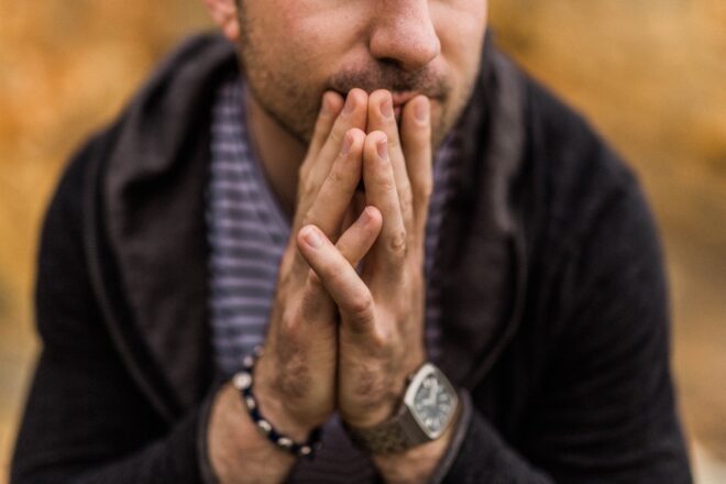 Man clasping hands under chin